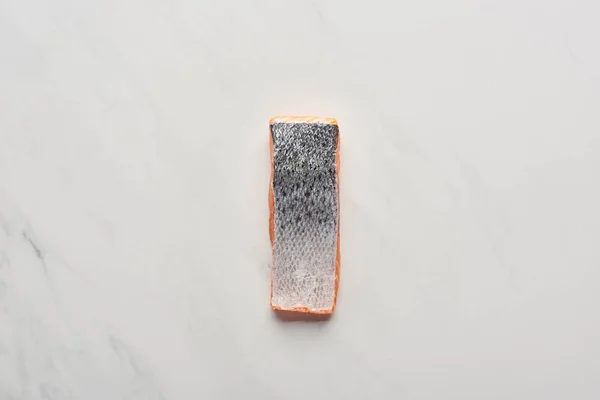 Vista superior de bife de salmão fresco cru com escamas de peixe na superfície de mármore branco — Fotografia de Stock