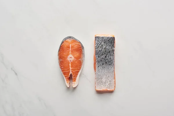 Top view of raw fresh salmon steaks with fish scales on white marble surface — Stock Photo