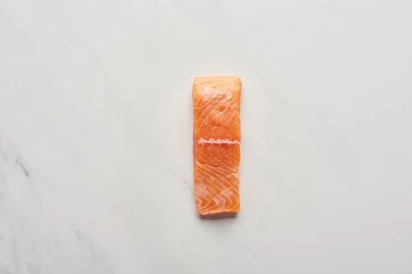 Top view of uncooked fresh salmon steak on white marble surface — Stock Photo