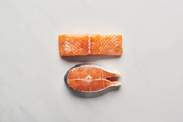 Top view of raw salmon steaks on white marble surface — Stock Photo