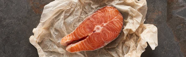 Top view of raw salmon steak on bakery paper on stone table, panoramic shot — Stock Photo