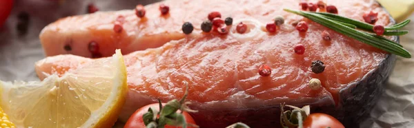 Vista da vicino di bistecca di salmone crudo con grani di pepe, limone e rosmarino, colpo panoramico — Foto stock