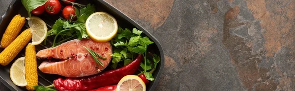 Top view of uncooked salmon with vegetables, lemon and herbs in grill pan, panoramic shot — Stock Photo