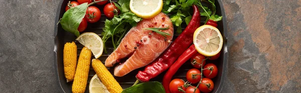 Top view of uncooked salmon steak with vegetables, lemon and herbs in grill pan, panoramic shot — Stock Photo