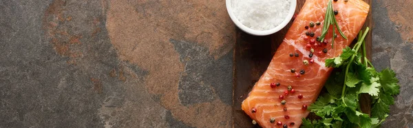 Top view of raw fresh salmon with peppercorns, parsley and salt on wooden cutting board, panoramic shot — Stock Photo