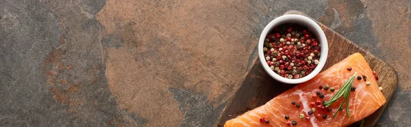 Vue du dessus du steak de saumon frais cru avec des grains de poivre sur planche à découper en bois, vue panoramique — Photo de stock