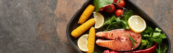 Top view of raw salmon steak with vegetables, lemon and herbs in grill pan, panoramic shot — Stock Photo