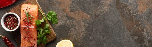 Vista superior de bife de salmão com pimenta, salsa em tábua de corte de madeira perto de limão e pimenta, tiro panorâmico — Fotografia de Stock