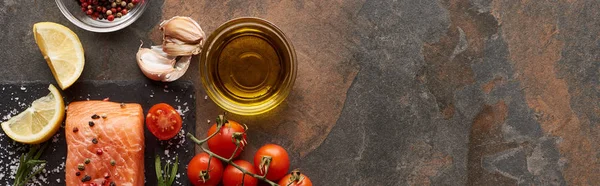 Top view of raw salmon with seasoning, oil, garlic and tomatoes on stone surface, panoramic shot — Stock Photo