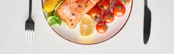 Top view of raw salmon steak with  vegetables on plate near cutlery on marble table, panoramic shot — Stock Photo