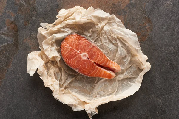 Top view of raw salmon steak on bakery paper on stone table — Stock Photo