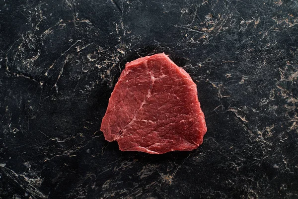 Vista superior del filete de carne cruda en la superficie de mármol negro - foto de stock