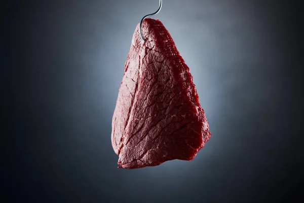 Raw beef sirloin on hook on dark black background — Stock Photo