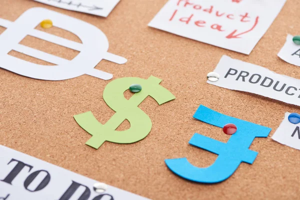 Tarjetas de papel de color con signos de moneda fijados en el tablero de oficina de corcho - foto de stock