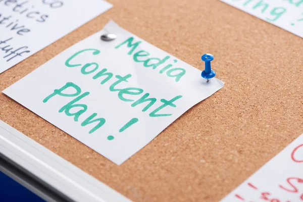 Paper card with media content plan inscription pinned on cork office board — Stock Photo