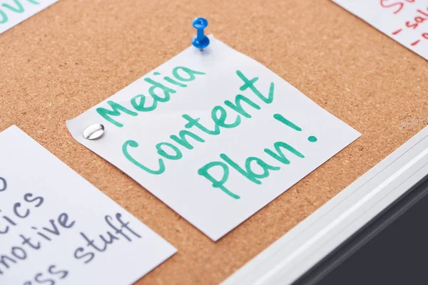 Paper card with media content plan lettering pinned on cork office board — Stock Photo