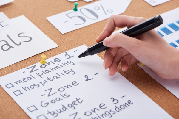 Cropped view of woman holding black highlighter near cards on cork board — Stock Photo