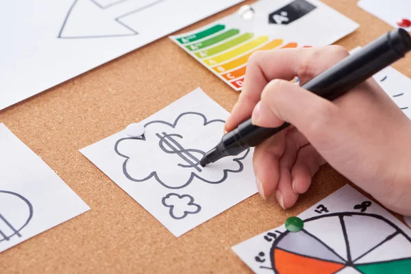 Cropped view of woman writing with black highlighter dollar sign in cloud on card pinned on cork board — Stock Photo