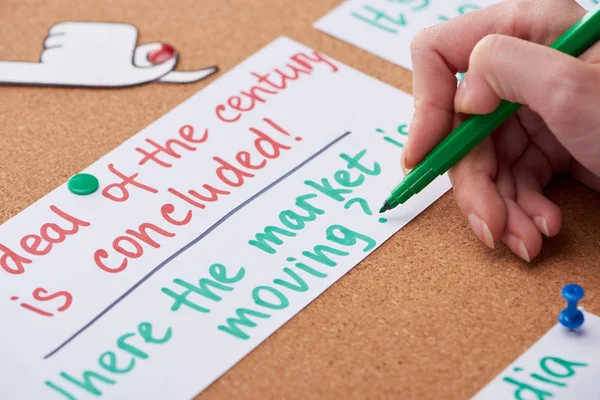 Cropped view of woman writing work notes on card pinned on cork board — Stock Photo