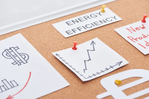 Бумажные карточки с текстом энергоэффективности и увеличением диаграммы, прикрепленной на пробковую доску офиса — стоковое фото