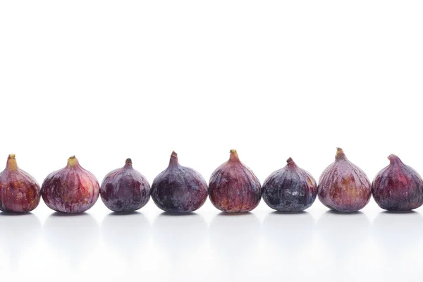 Figos deliciosos inteiros maduros em linha no fundo branco — Fotografia de Stock