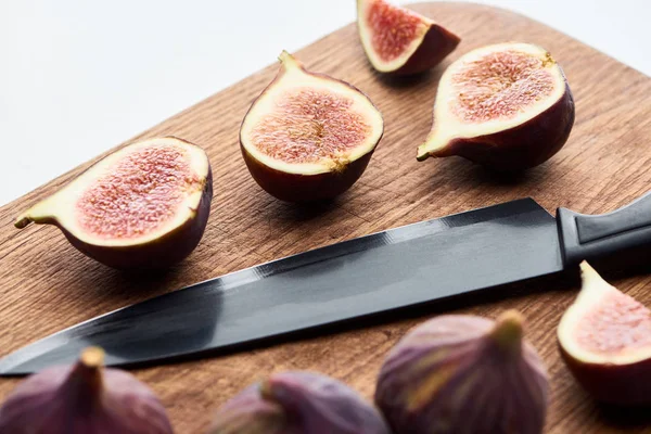 Figues entières mûres et coupées délicieuses sur planche à découper en bois avec couteau isolé sur blanc — Photo de stock