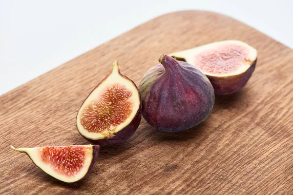 Ripe whole and cut delicious figs on wooden chopping board isolated on white — Stock Photo