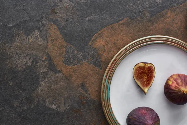 Vue de dessus de figues mûres délicieuses sur plaque blanche sur fond de pierre — Photo de stock