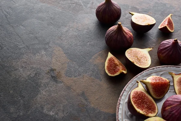 Ripe whole and cut delicious figs on white plate stone background — Stock Photo