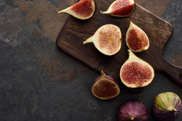 Vue du dessus de figues fraîches et délicieuses mûres sur planche à découper sur fond de pierre — Photo de stock