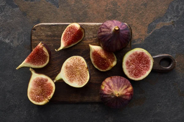 Vue du dessus de figues délicieuses coupées mûres sur planche à découper sur fond de pierre — Photo de stock