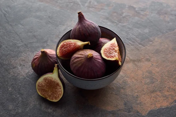 Ripe whole and cut delicious figs in bowl on stone background — Stock Photo