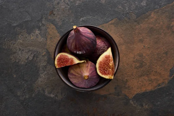 Vue du dessus de figues entières mûres et coupées délicieuses dans un bol sur fond de pierre — Photo de stock