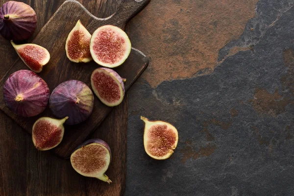 Top view of ripe whole and cut delicious figs and wooden brown cutting boards on stone background — Stock Photo