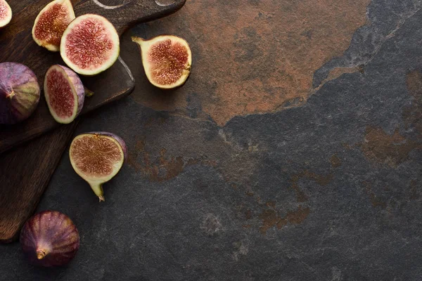 Vista superior de higos maduros deliciosos y tablas de cortar marrón madera sobre fondo de piedra - foto de stock