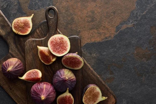 Top view of ripe whole and cut delicious figs and cutting boards on stone background — Stock Photo