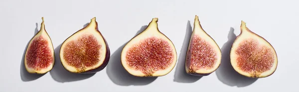 Panoramic shot of ripe cut delicious figs in row on white background — Stock Photo