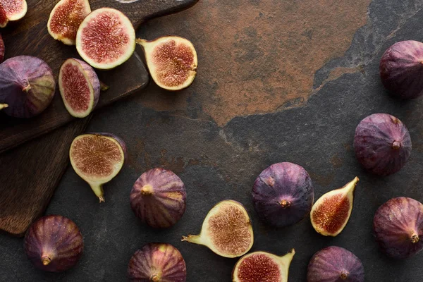 Vista superior de higos maduros enteros y cortados deliciosos cerca de tablas de cortar sobre fondo de piedra - foto de stock