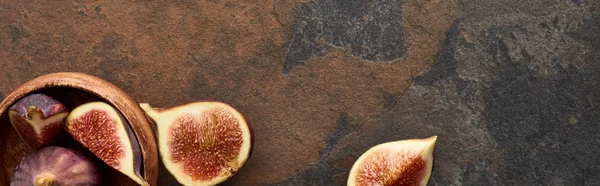 Panoramic shot of ripe whole and cut delicious figs near wooden bowl on stone background — Stock Photo