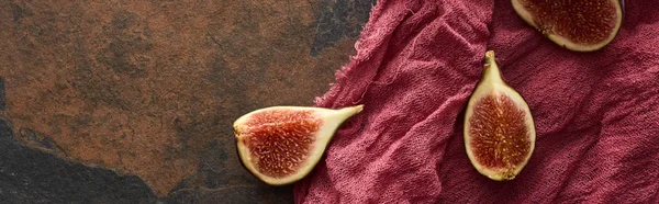 Panoramic shot of cut delicious figs on rustic red cloth on stone background — Stock Photo