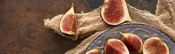 Plan panoramique de figues mûres coupées sur plaque blanche avec tissu rustique sur fond de pierre — Photo de stock