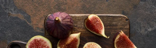 Panoramic shot of ripe fresh delicious figs on cutting board on stone background — Stock Photo
