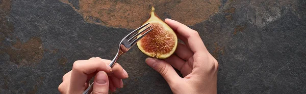 Cropped view of woman holding fork and ripe delicious fig half on stone background, panoramic shot — Stock Photo