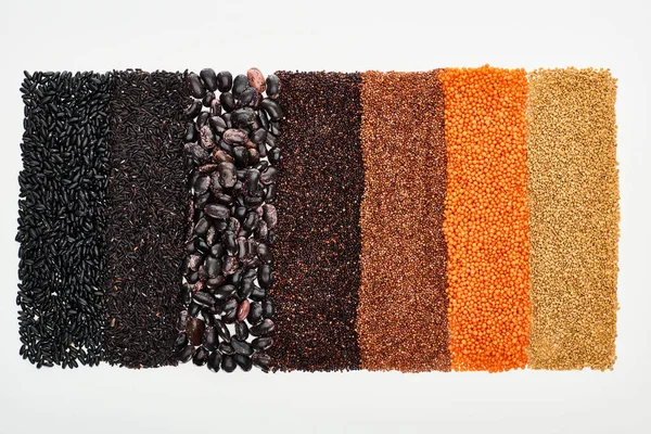Vista superior de frijoles negros, arroz, quinua, trigo sarraceno y lentejas rojas aisladas sobre blanco - foto de stock