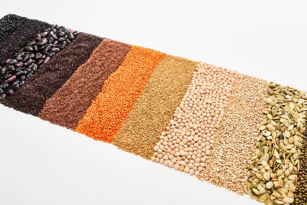 Variedad de frijoles negros, arroz, quinua, trigo sarraceno, garbanzo, semillas de calabaza y lentejas rojas aisladas en blanco - foto de stock