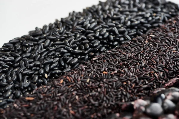 Raw wild rice near black beans isolated on white — Stock Photo