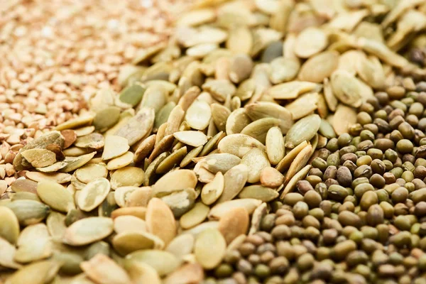 Vue rapprochée des graines de citrouille crues près de maash et de sarrasin vert — Photo de stock