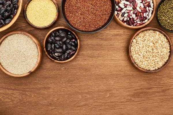 Vue de dessus des bols avec des haricots et des grains sur la surface en bois avec espace de copie — Photo de stock