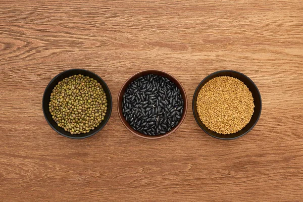 Top view of bowls with legumes and cereal on wooden surface — Stock Photo