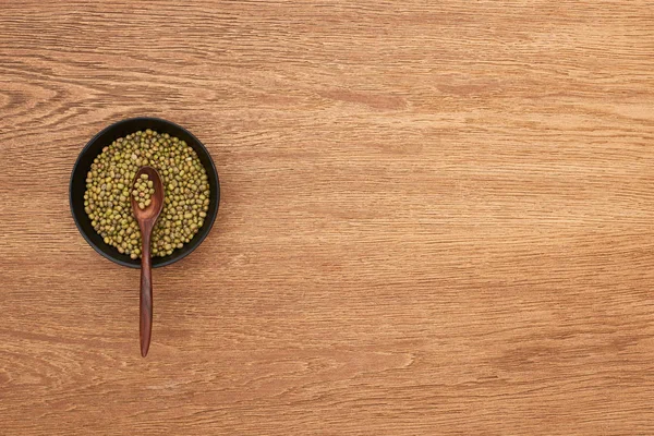 Vue du dessus du bol avec haricots moong avec cuillère sur la surface en bois — Photo de stock